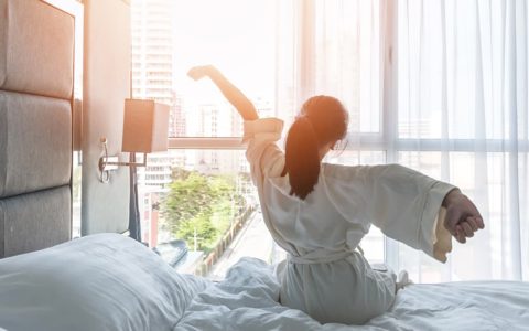 mujer en cama de hotel cortina transparente